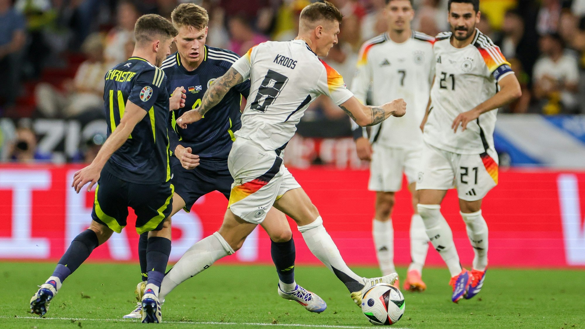 Deutschlands Spieler Toni Kroos (M) setzt sich gegen Schottlands Ryan Christie (l) und Scott McTominay durch.