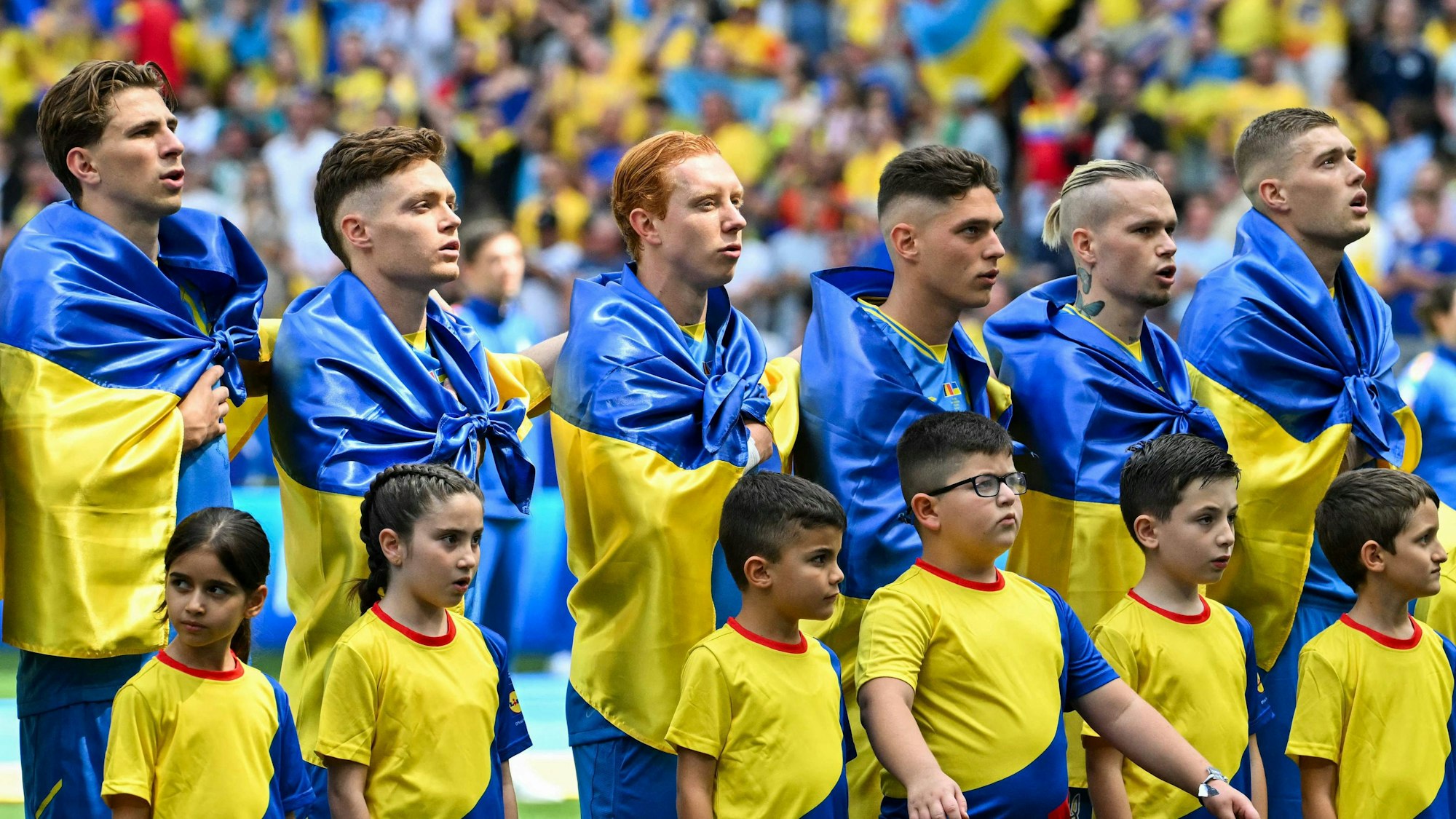 Die ukrainischen Spieler mit Flaggen um die Schultern bei der Hymne.