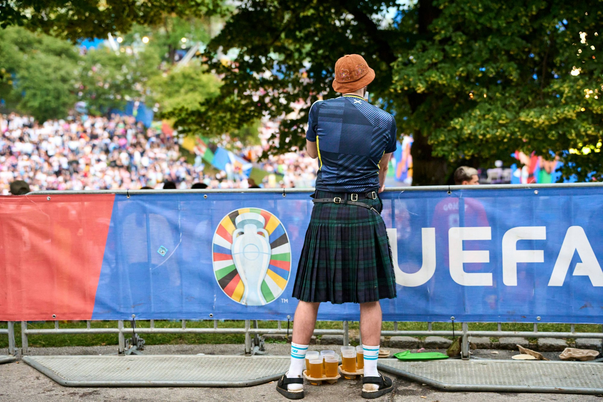Ein Schottland-Fan im Kilt hat Bierbecher vor sich.
