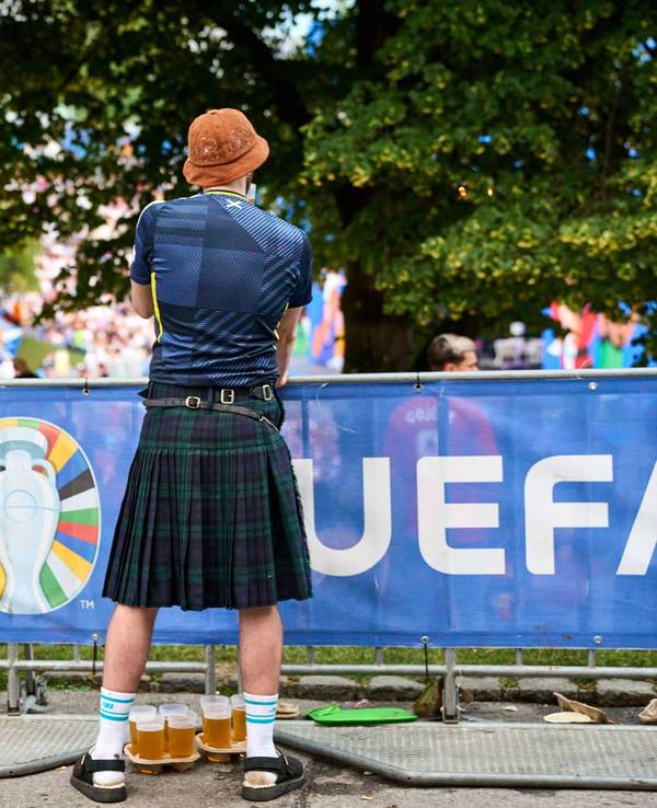 Ein Schottland-Fan im Kilt hat Bierbecher vor sich.