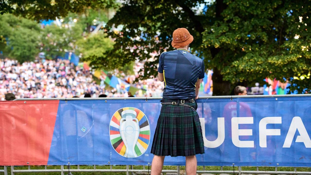 Ein Schottland-Fan im Kilt hat Bierbecher vor sich.