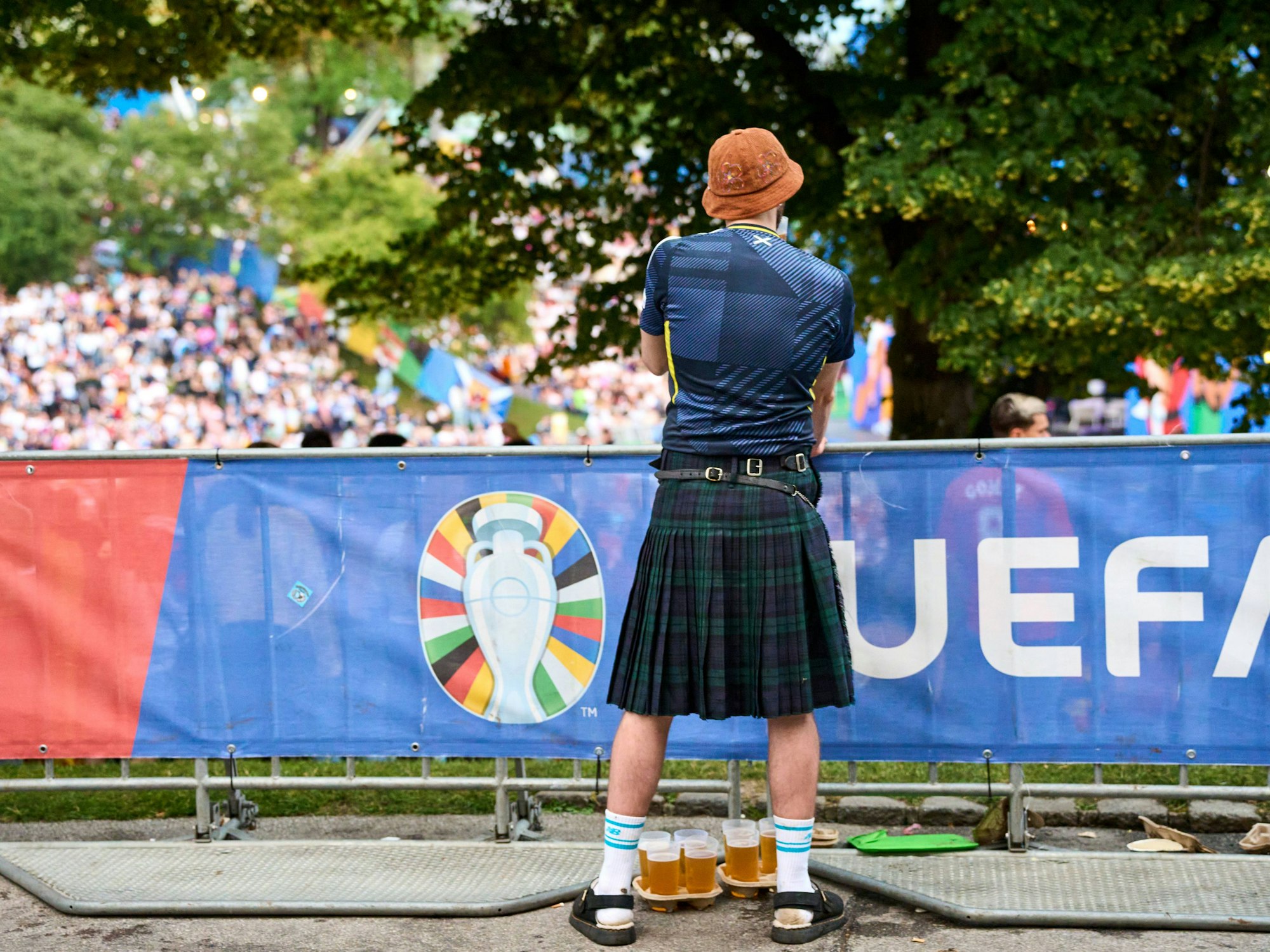 Ein Schottland-Fan im Kilt hat Bierbecher vor sich.