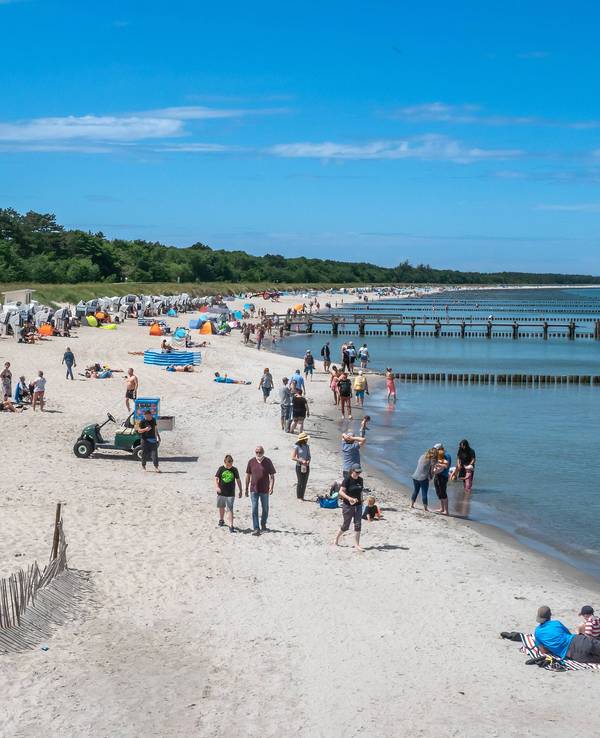 Menschen liegen an der Ostsee am Strand.