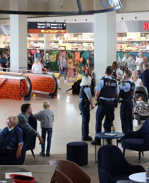 Menschen gehen durch den Flughafen Köln/Bonn, auch eine Streife der Bundespolizei ist zu sehen.