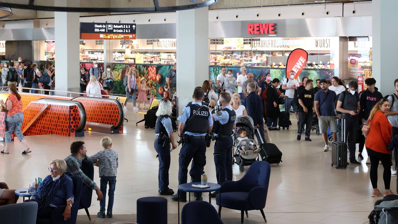 Menschen gehen durch den Flughafen Köln/Bonn, auch eine Streife der Bundespolizei ist zu sehen.