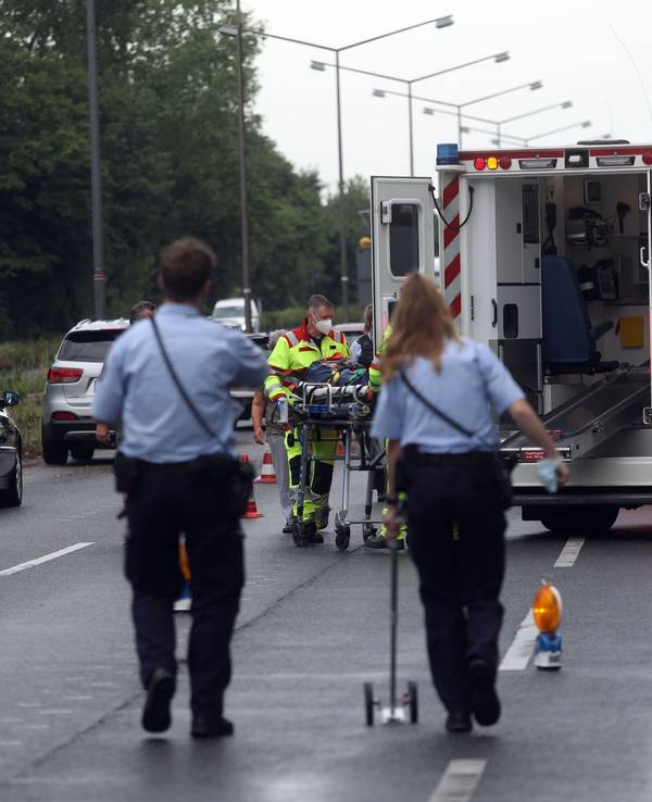 Ein Rettungswagen steht auf einer Straße, zwei Einsatzkräfte der Polizei nehmen Unfallspuren auf.