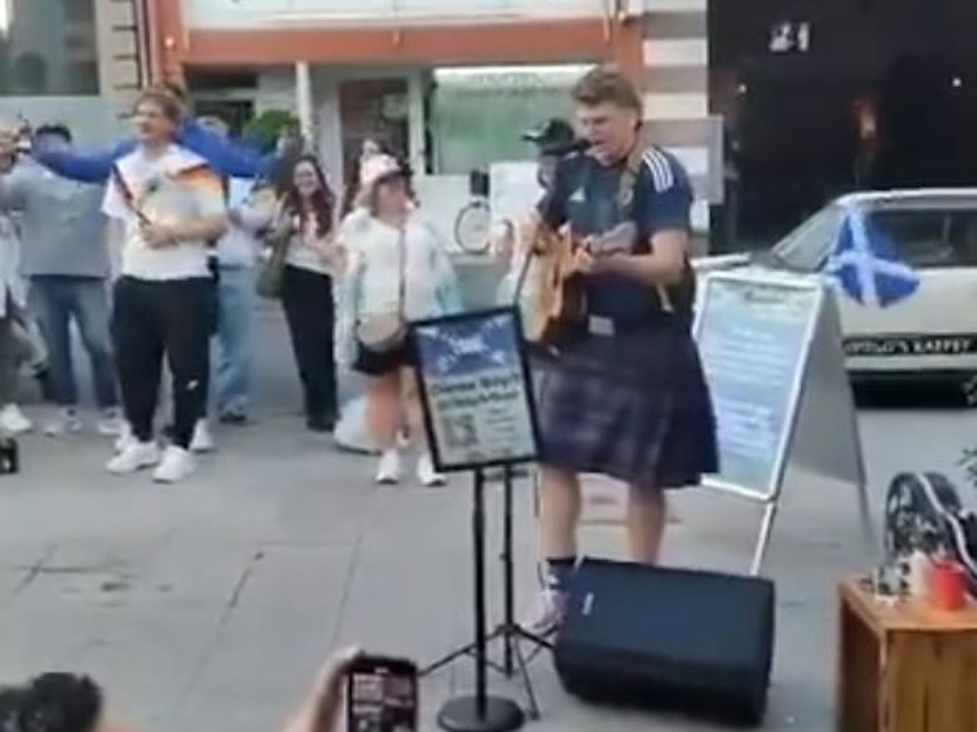 Ein Schottland-Fan steht in Köln mit Gitarre auf der Straße.