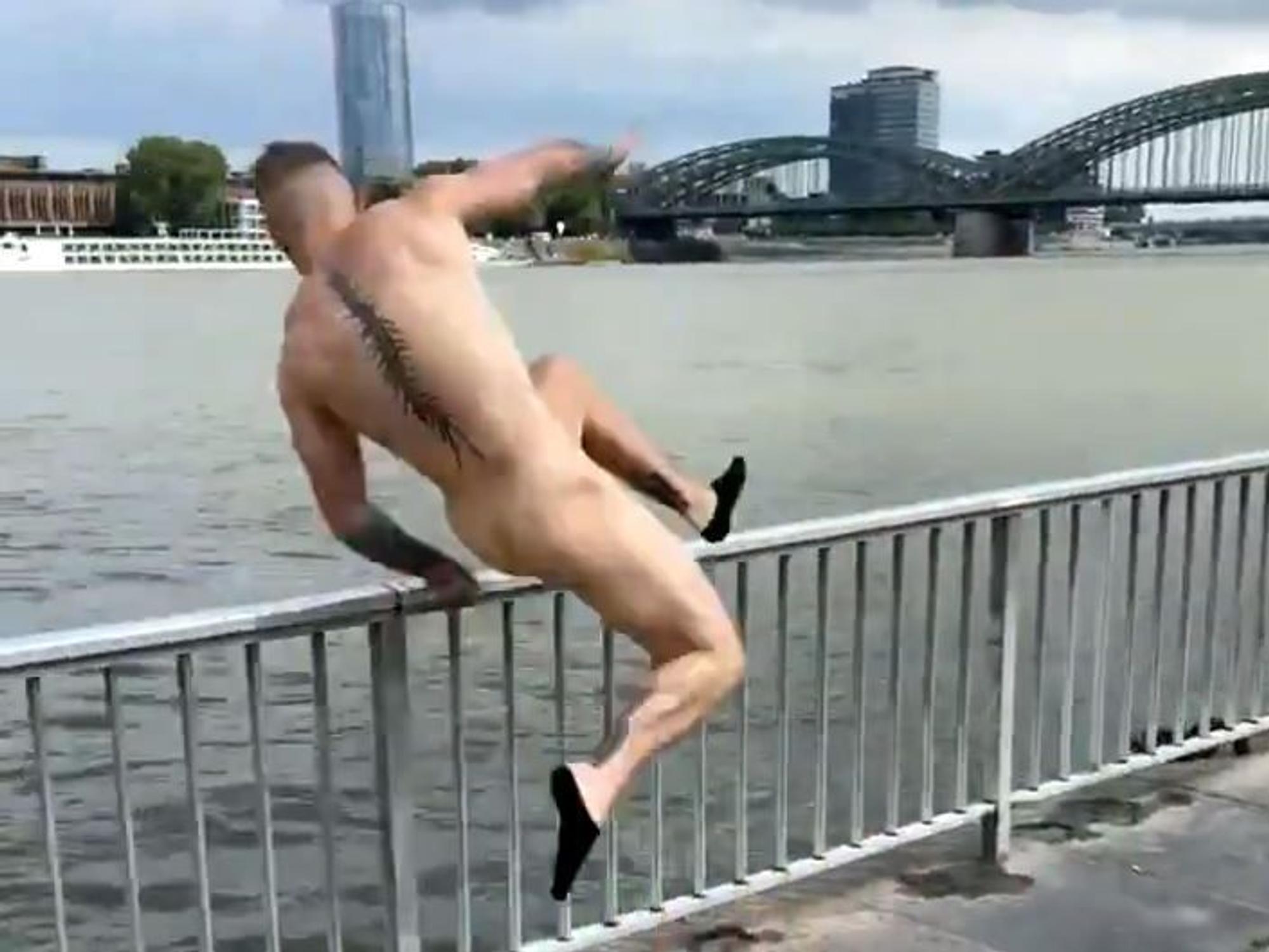 Ein Mann springt am linken Rheinufer ins Wasser.
