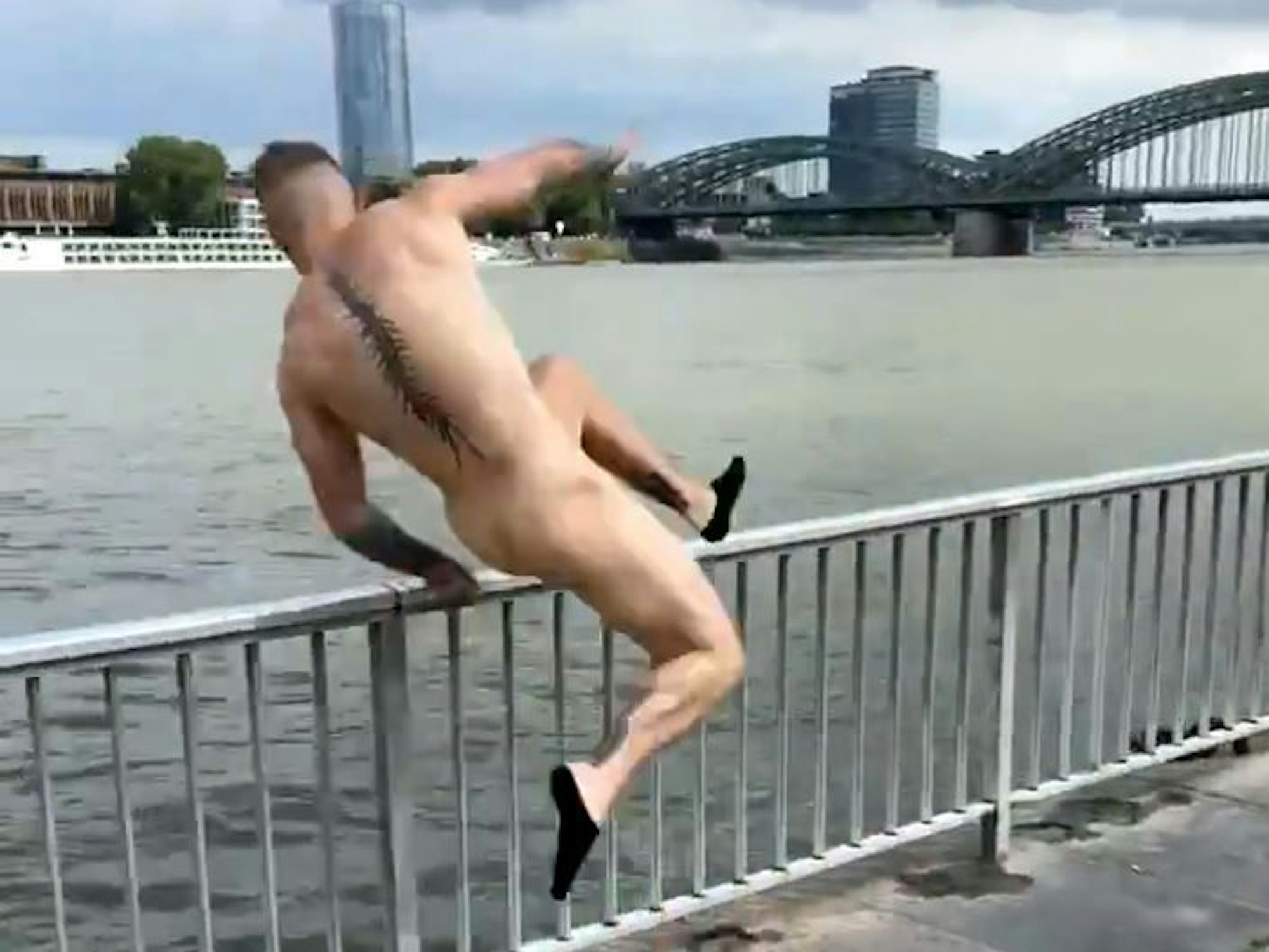 Ein Mann springt am linken Rheinufer ins Wasser.