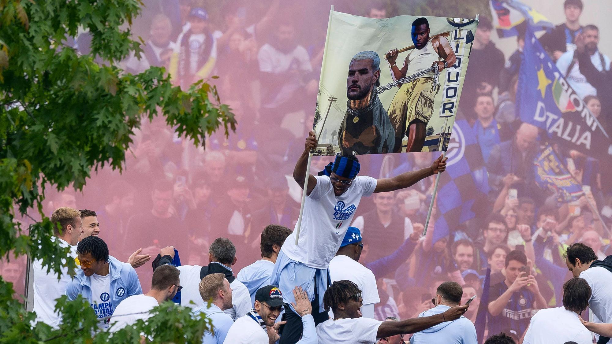 Denzel Dumfries (M.) hält ein Plakat mit beiden Händen hoch.