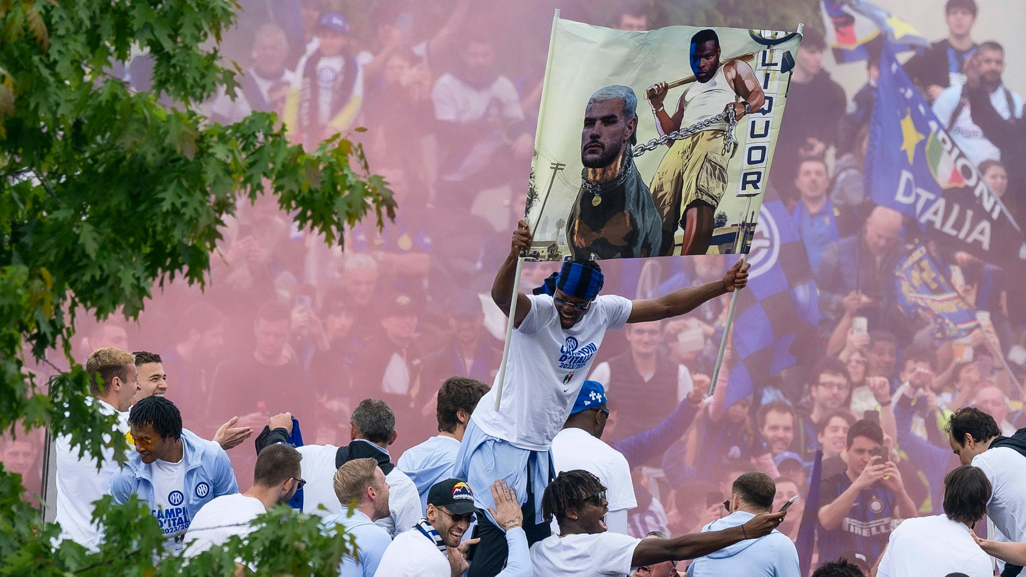 Denzel Dumfries (M.) hält ein Plakat mit beiden Händen hoch.