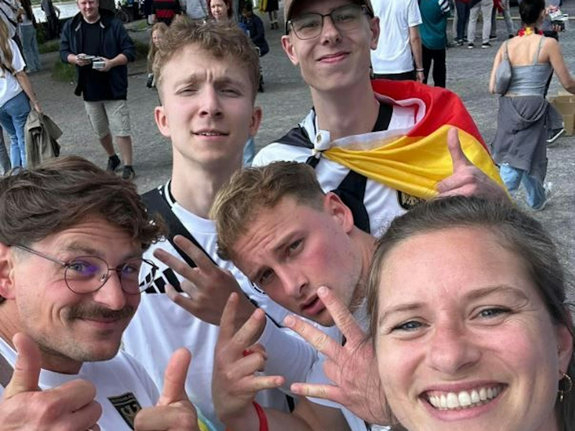 Fünf Deutschland-Fans mit Trikots machen ein Selfie am Tanzbrunnen in Köln.
