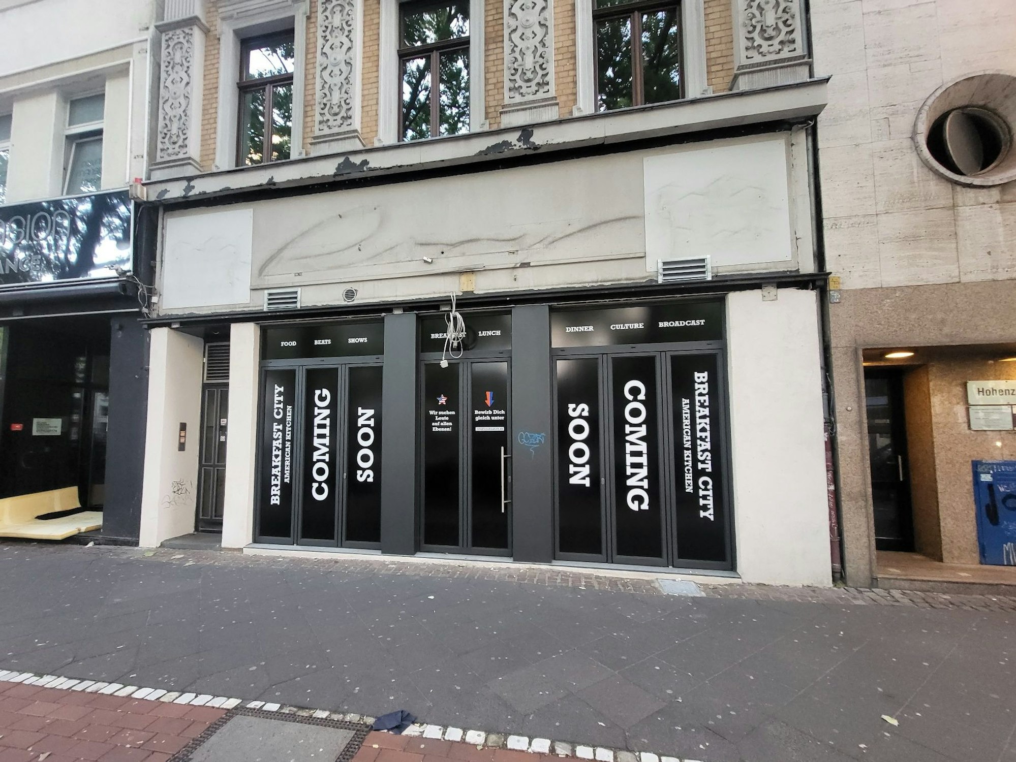 Fassade des ehemaligen Roxy an der Aachener Straße in Köln. Die Fassade weist auf einen bald öffnenden Frühstücksladen hin.