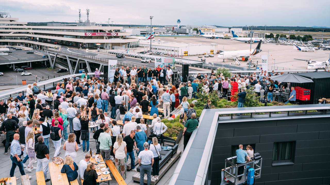 Viele Menschen auf der Dachterrassen eines Hotels am Flughafen Köln/Bonn. Im Hintergrund sind Flugzeuge zu sehen.