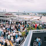Viele Menschen auf der Dachterrassen eines Hotels am Flughafen Köln/Bonn. Im Hintergrund sind Flugzeuge zu sehen.