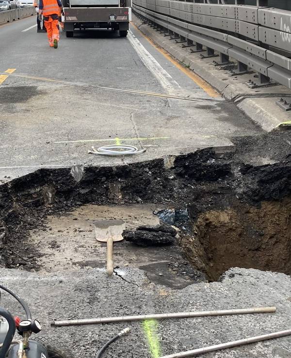 Arbeiter stehen neben dem Loch in der Fahrbahn der Autobahn 3 in Duisburg.