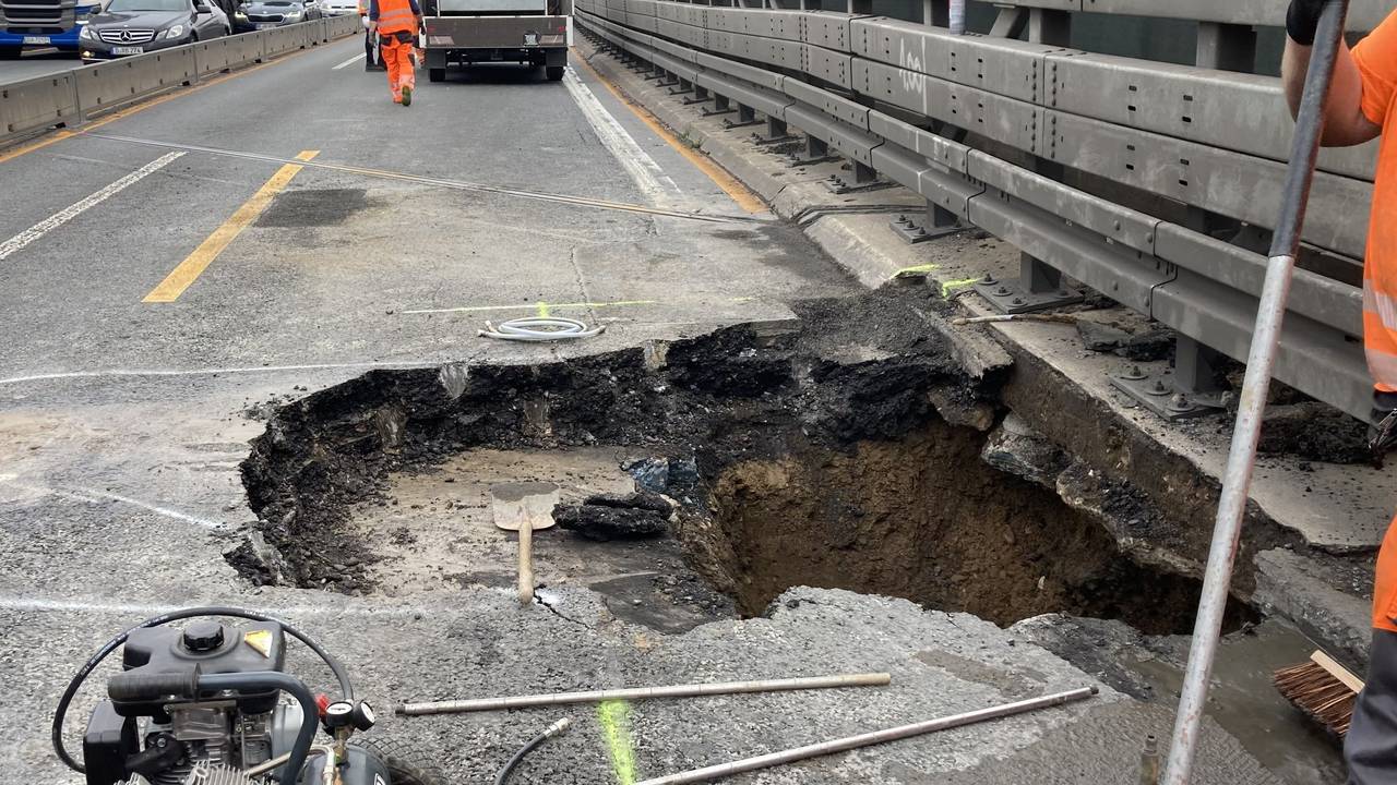Arbeiter stehen neben dem Loch in der Fahrbahn der Autobahn 3 in Duisburg.