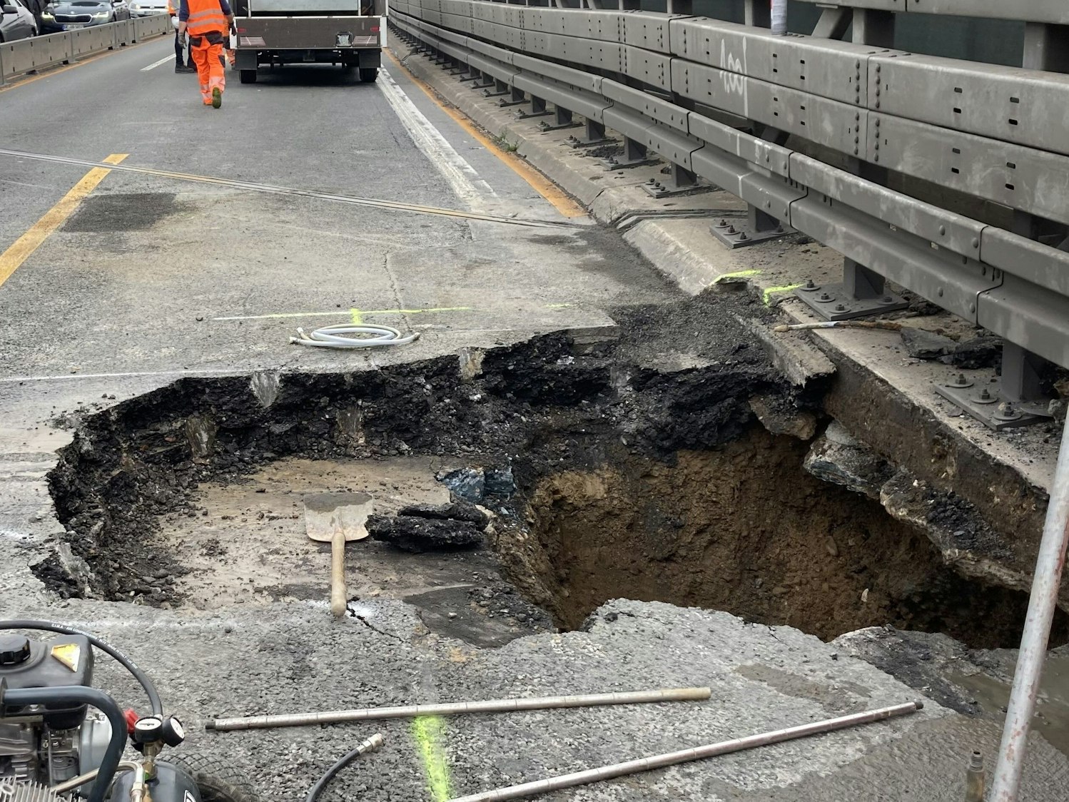 Arbeiter stehen neben dem Loch in der Fahrbahn der Autobahn 3 in Duisburg.