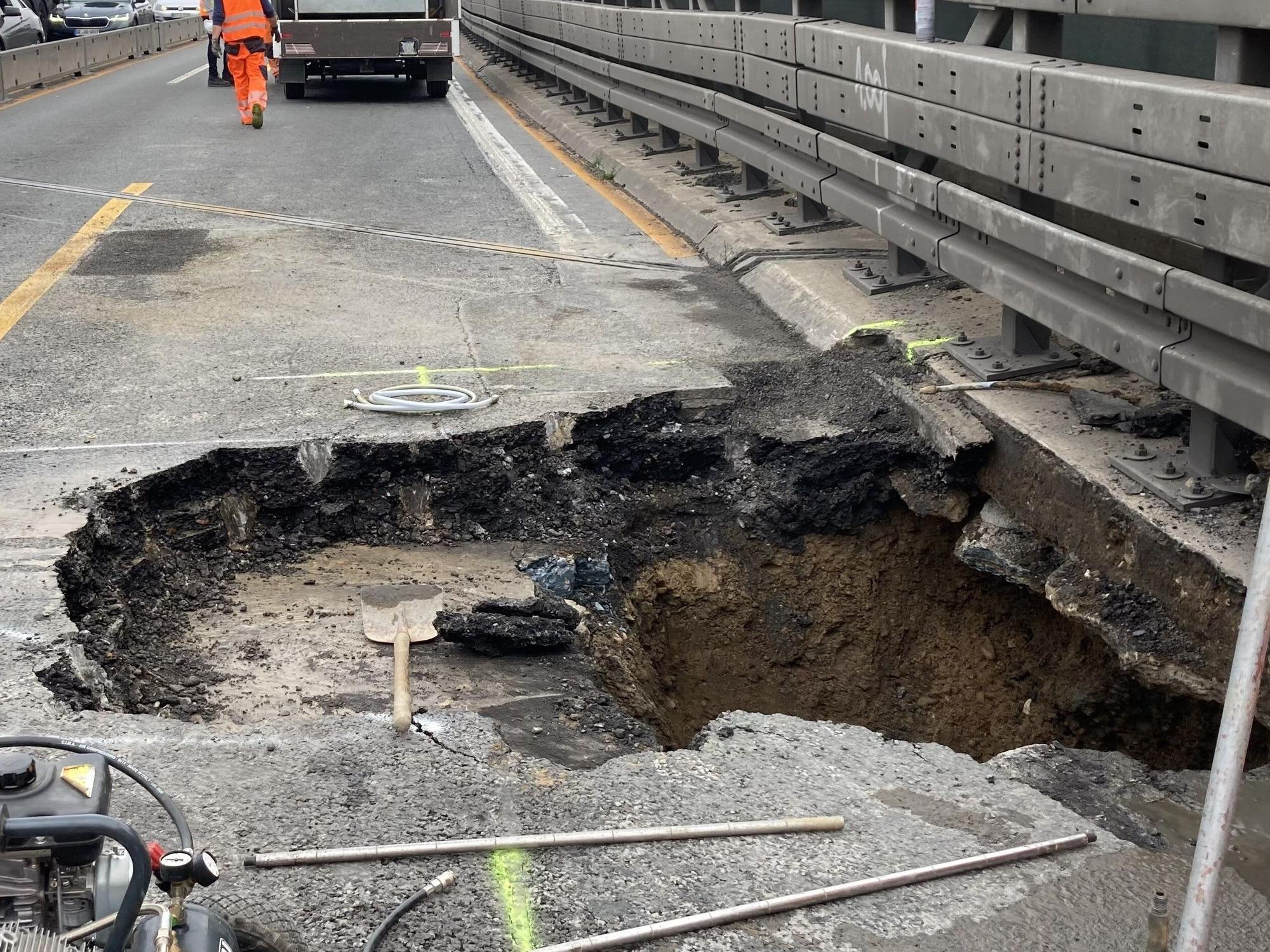 Arbeiter stehen neben dem Loch in der Fahrbahn der Autobahn 3 in Duisburg.