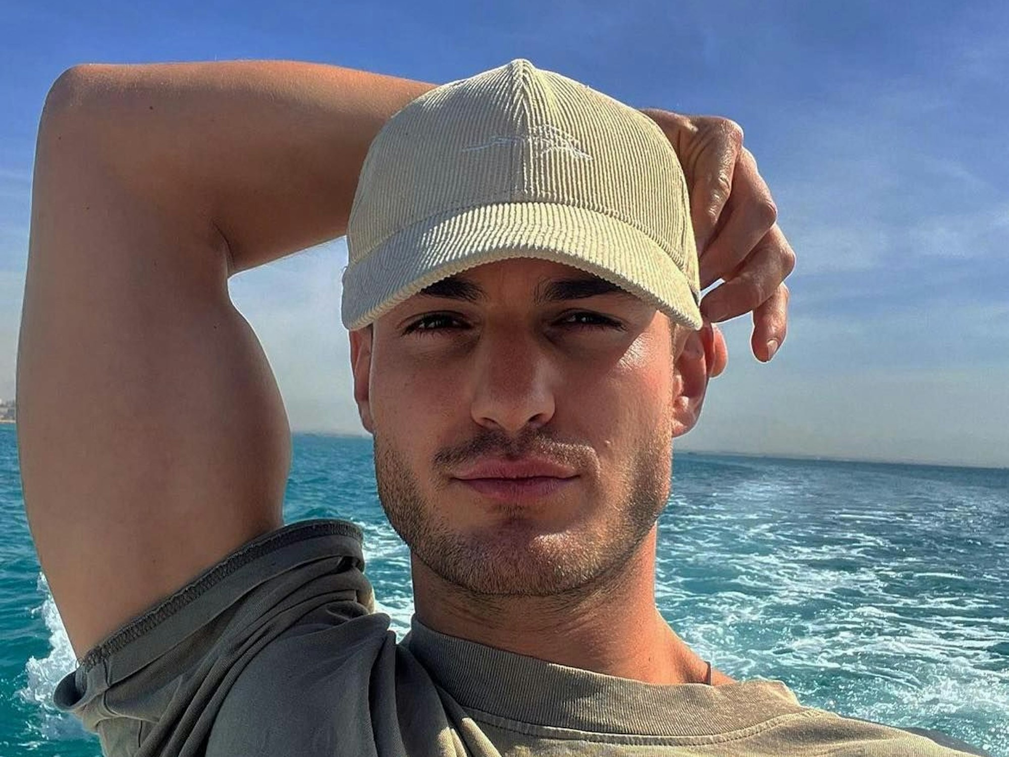 Can Kaplan mit Käppi – hier auf einem Foto, das der Unternehmer am 24. November 2023 auf seinem Instagram-Account veröffentlicht hat – schaut grinsend in die Kamera. Im Hintergrund sieht man das Meer.