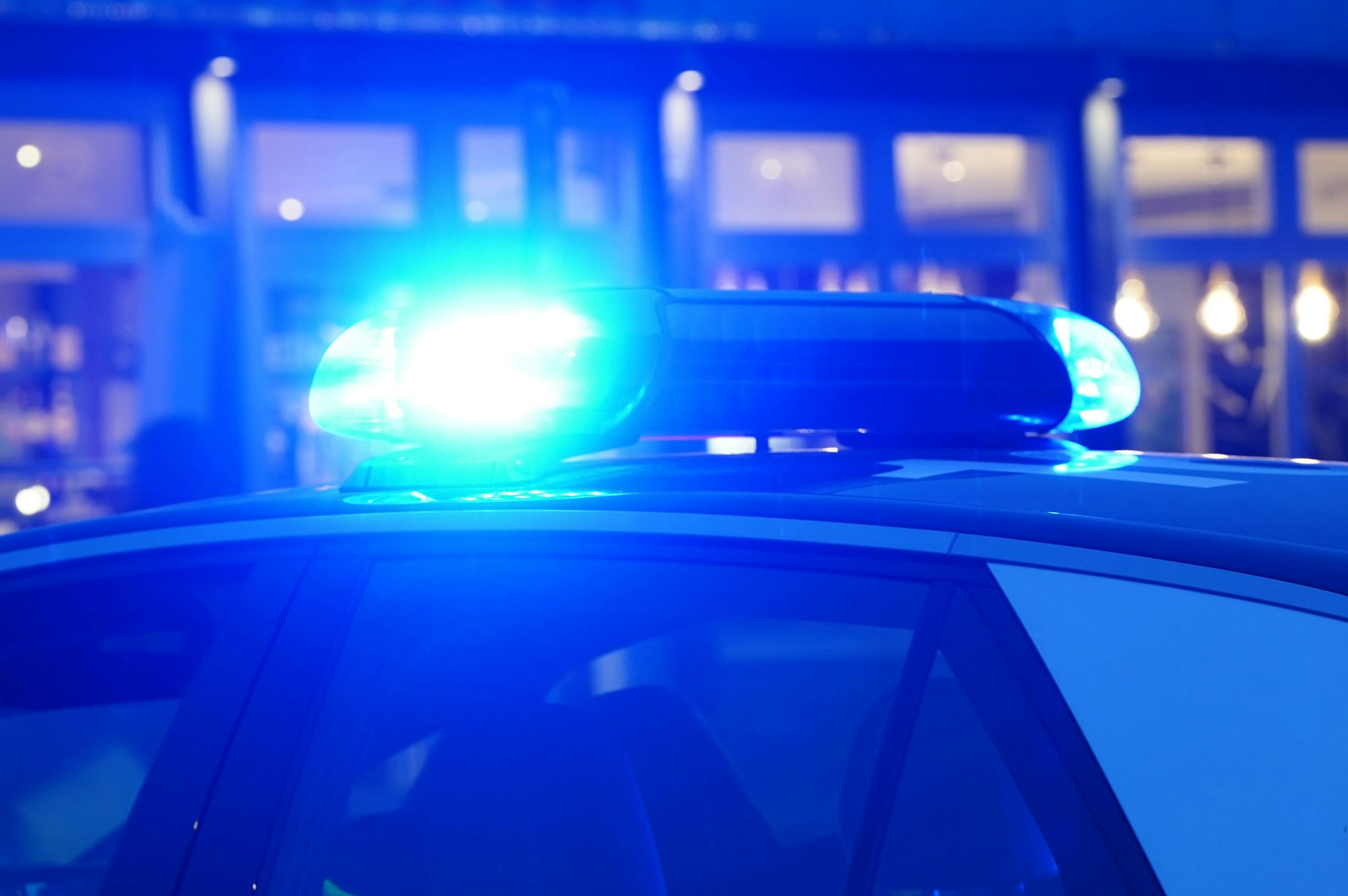 Ein Blaulicht leuchtet auf dem Dach eines Polizeiautos während einer Polizeiabsperrung.