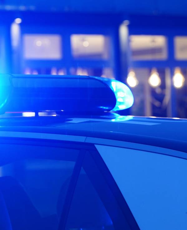 Ein Blaulicht leuchtet auf dem Dach eines Polizeiautos während einer Polizeiabsperrung.