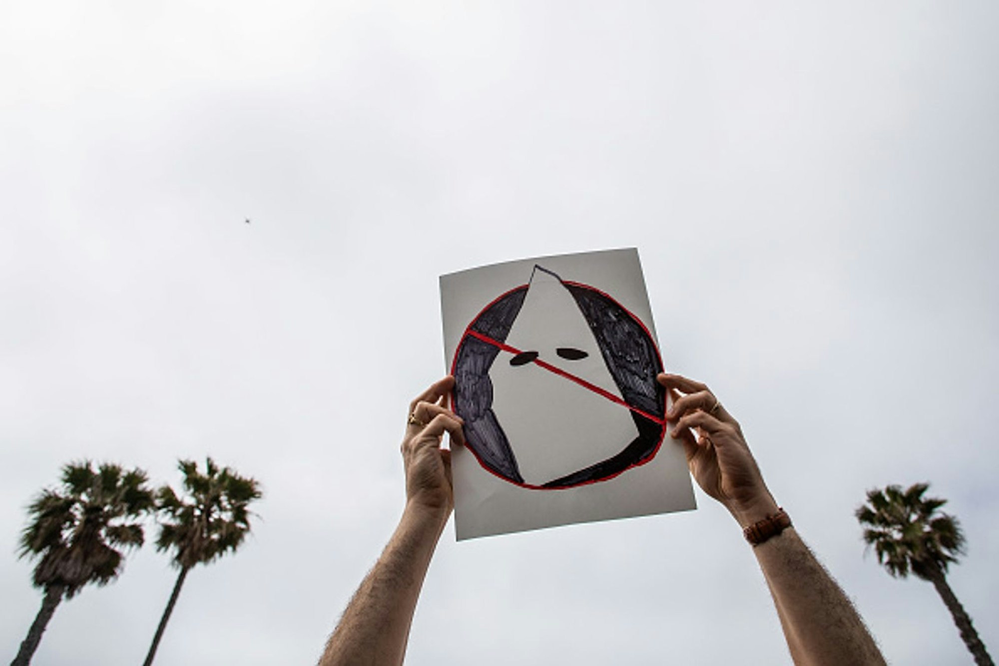 Ein Antirassist hält im April 2021 in Huntington Beach, Kalifornien, ein Plakat gegen den Ku-Klux-Klan und dessen „White Supremacy“ in die Höhe. Ku-Klux-Klan-nahe Gruppen hatten zuvor Flugblätter verteilt. (Bild: 2021 Getty Images / Apu Gomes)