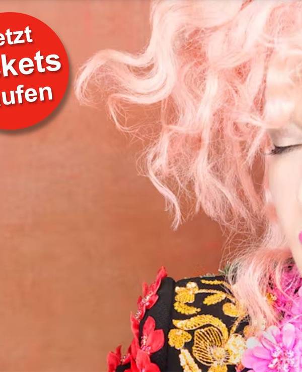 Cyndi Lauper trägt eine bunte Jacke und hat die Augen geschlossen.