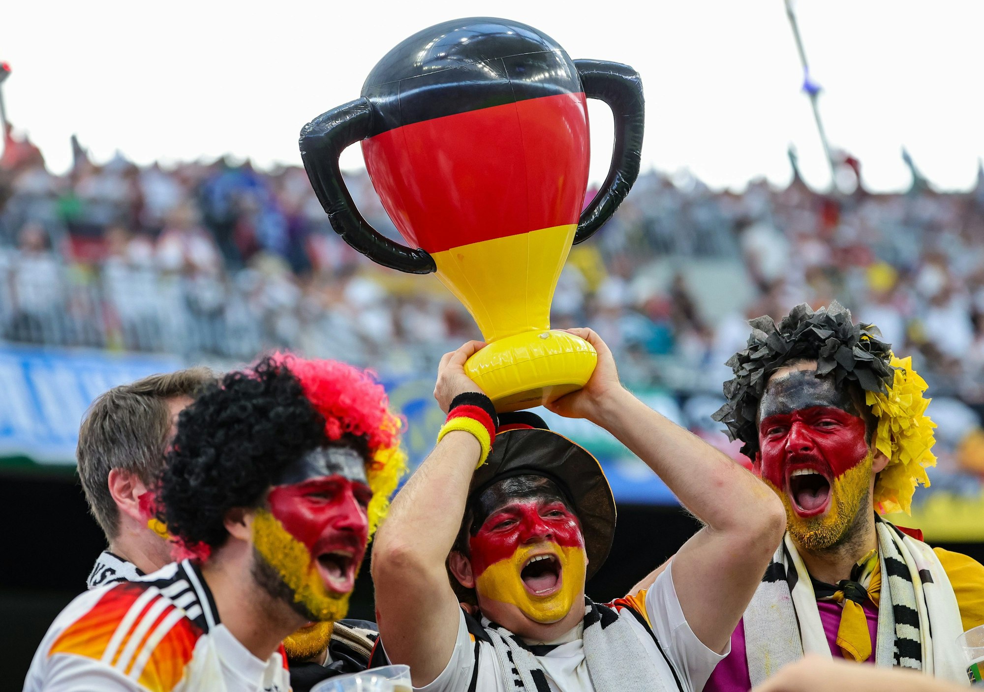Deutsche Fans jubeln mit einem aufgeblasenen Pokal.