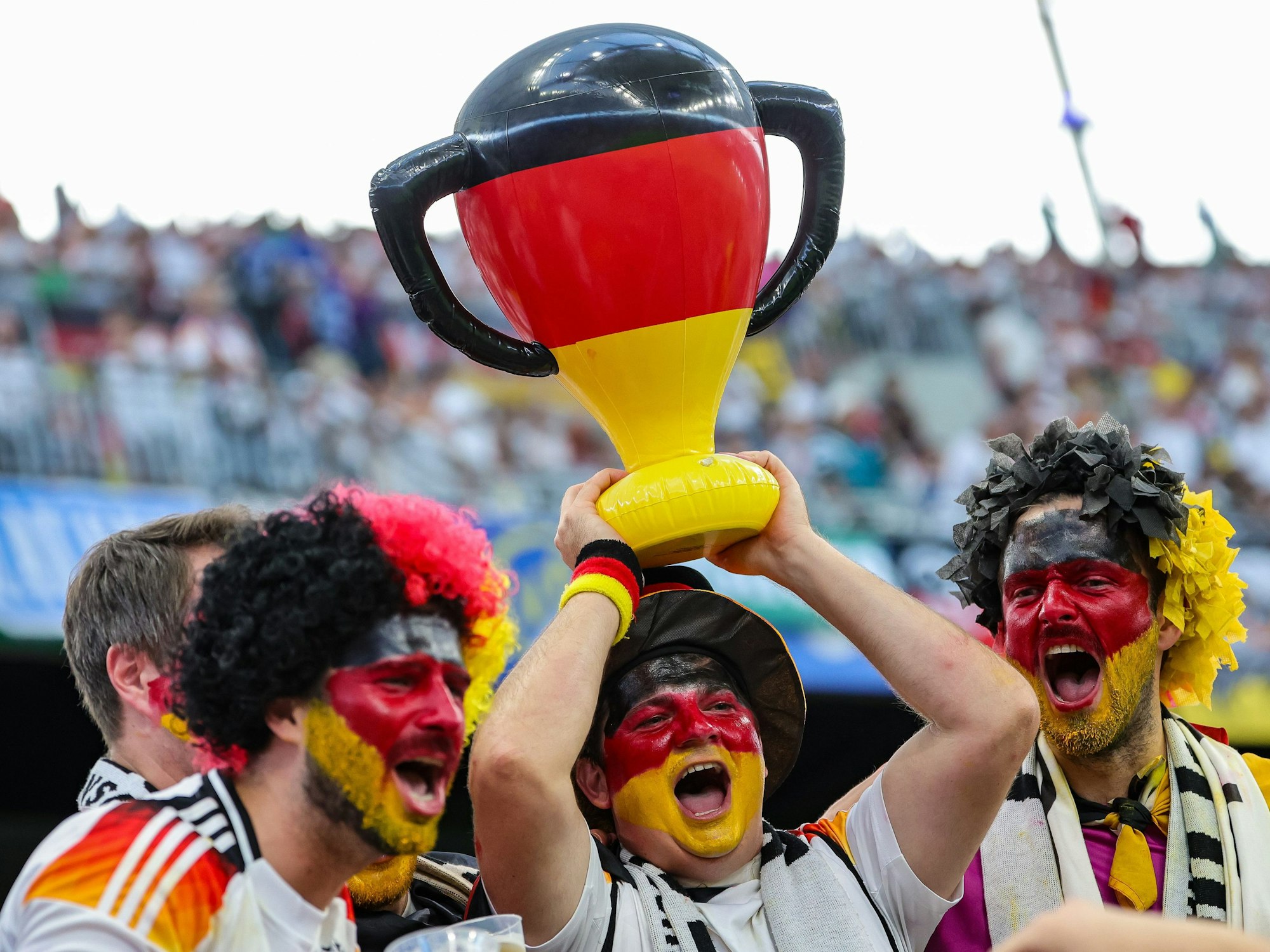 Deutsche Fans jubeln mit einem aufgeblasenen Pokal.