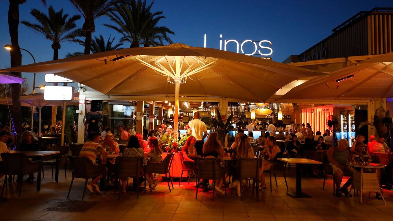 Menschen sitzen in einer Bar an der Strandpromenade von Palma (Mallorca).