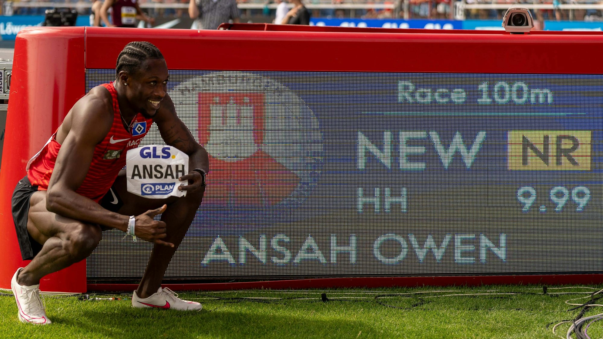 Owen Ansah hockt neben der Anzeige, die 9,99 Sekunden über 100 Meter für ihn ausweist.