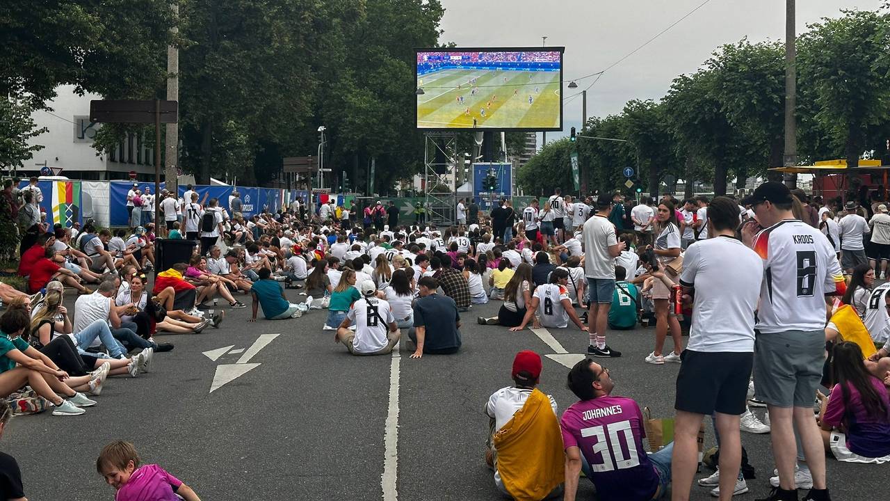 Menschen stehen beim Public Viewing auf einem Platz.