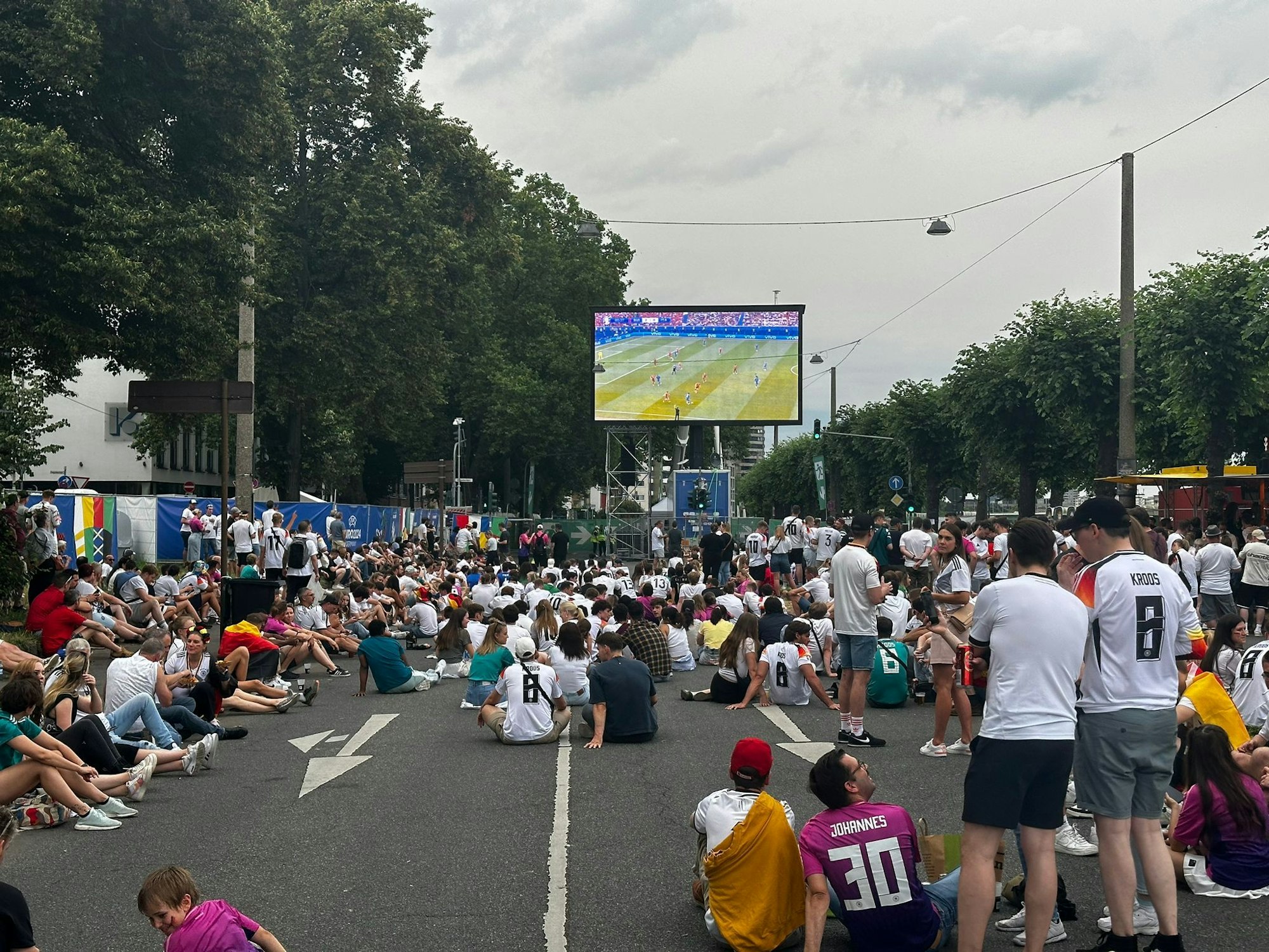 Menschen stehen beim Public Viewing auf einem Platz.