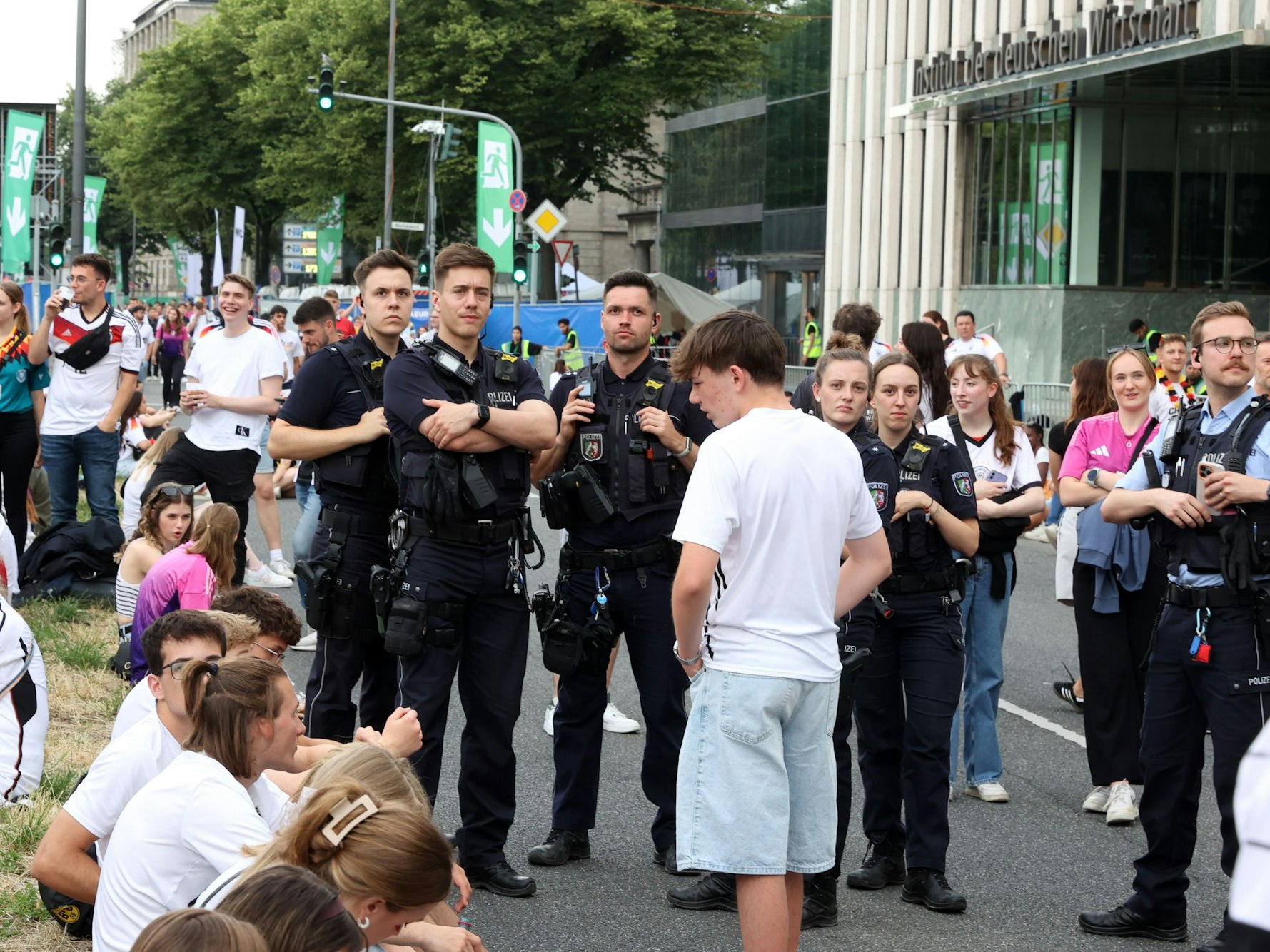Einsatzkräfte der Polizei stehen am Konrad-Adenauer-Ufer zwischen Fußballfans.