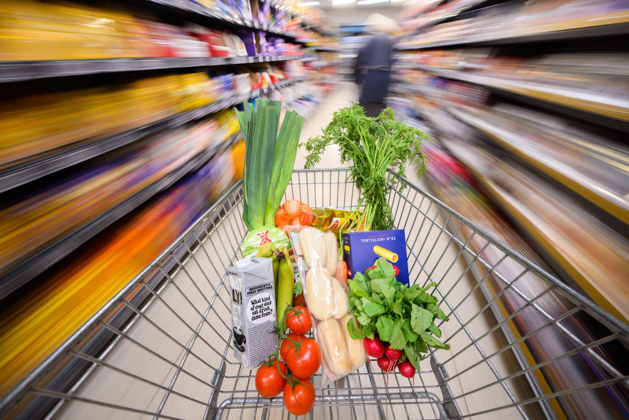 Ein mit Lebensmittel gefüllter Einkaufswagen wird durch einen Supermarkt geschoben, hier im August 2023 in Hannover.