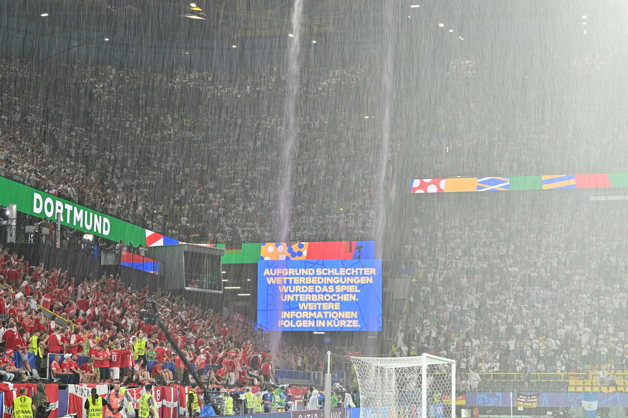 Der Regen strömt vom Dach des Dortmunders Stadions, auf der Anzeigetafel werden die Fans über die Spielunterbrechung informiert.
