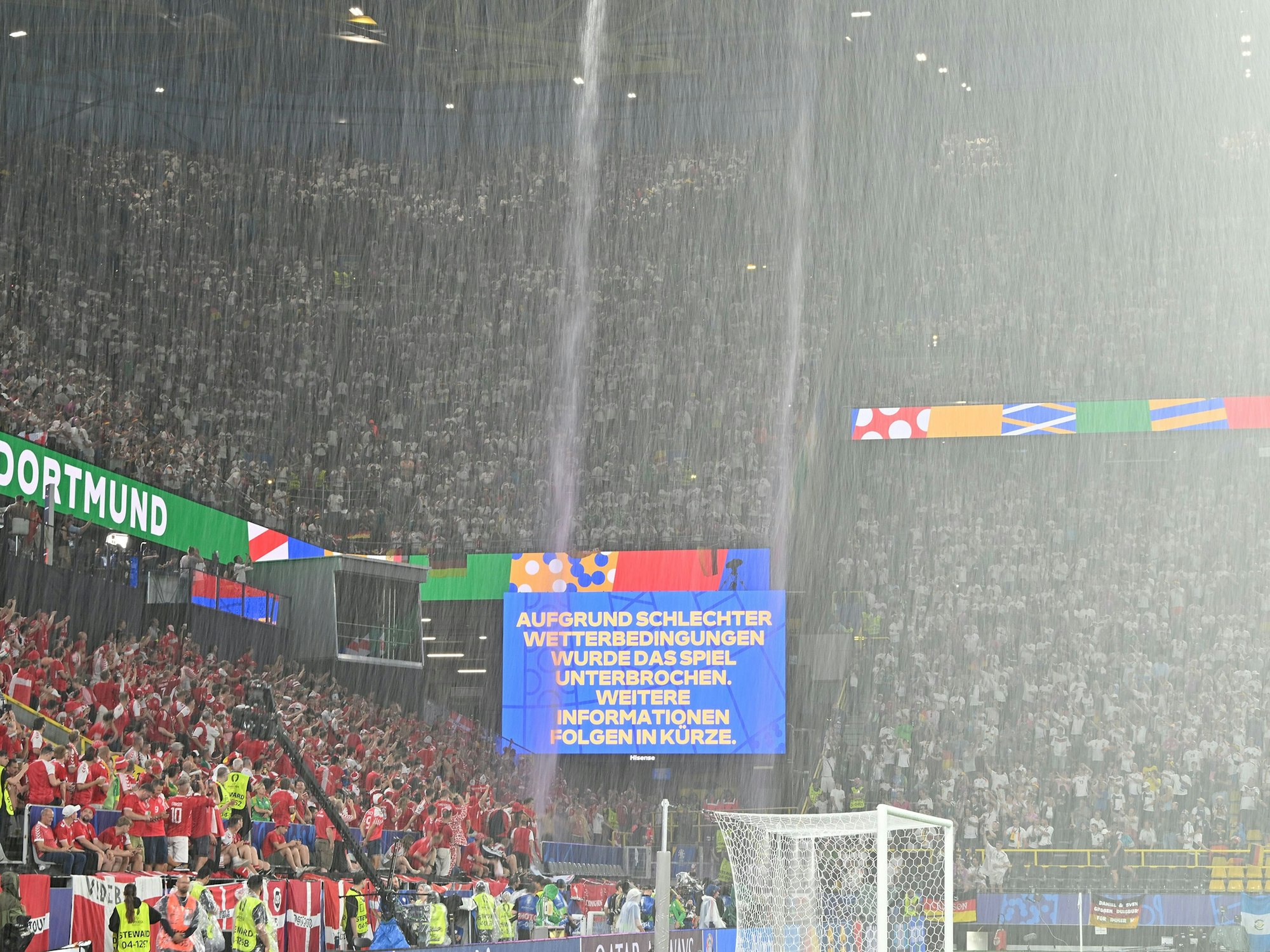Der Regen strömt vom Dach des Dortmunders Stadions, auf der Anzeigetafel werden die Fans über die Spielunterbrechung informiert.