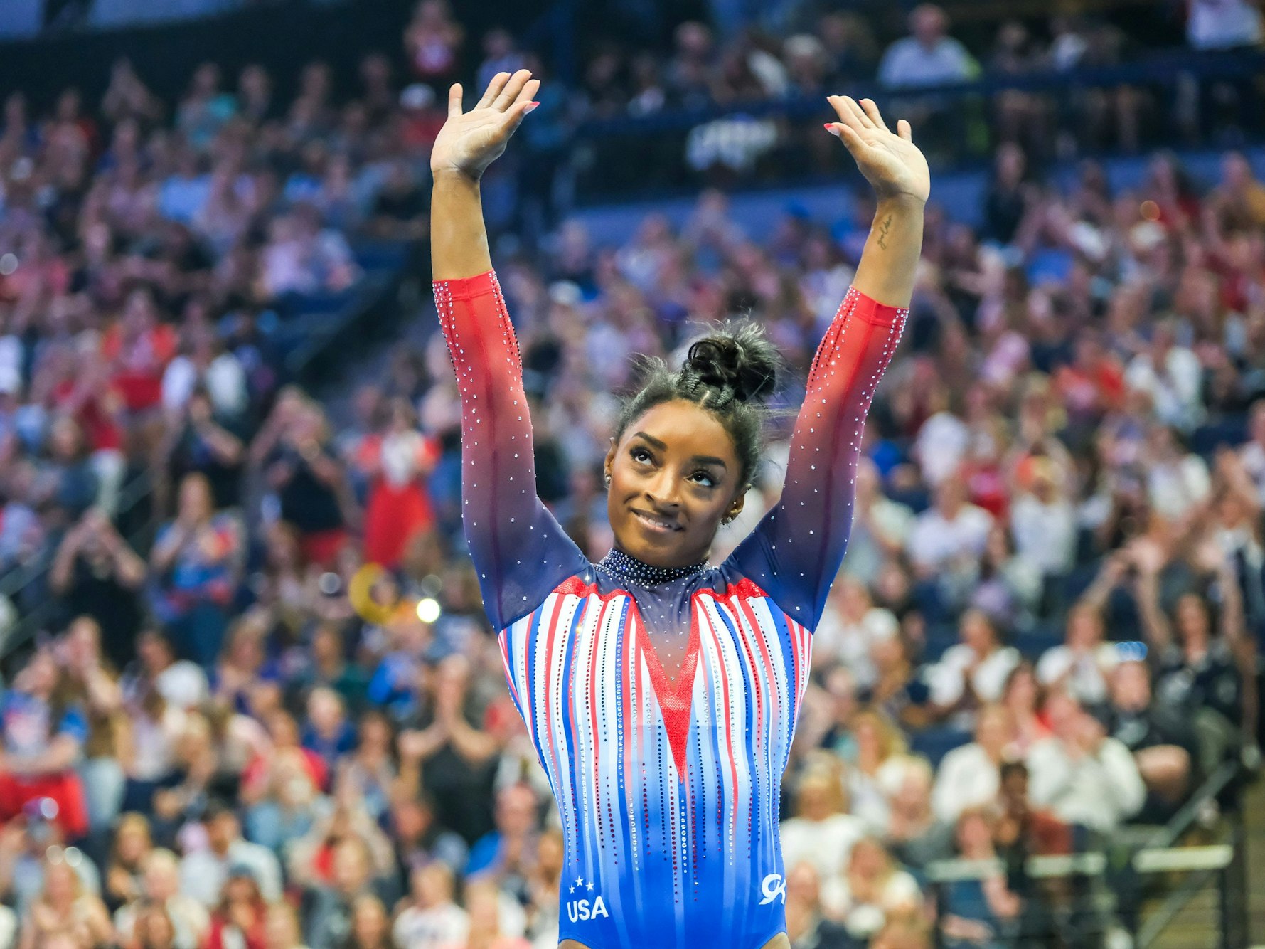 Simone Biles winkt dem Publikum.