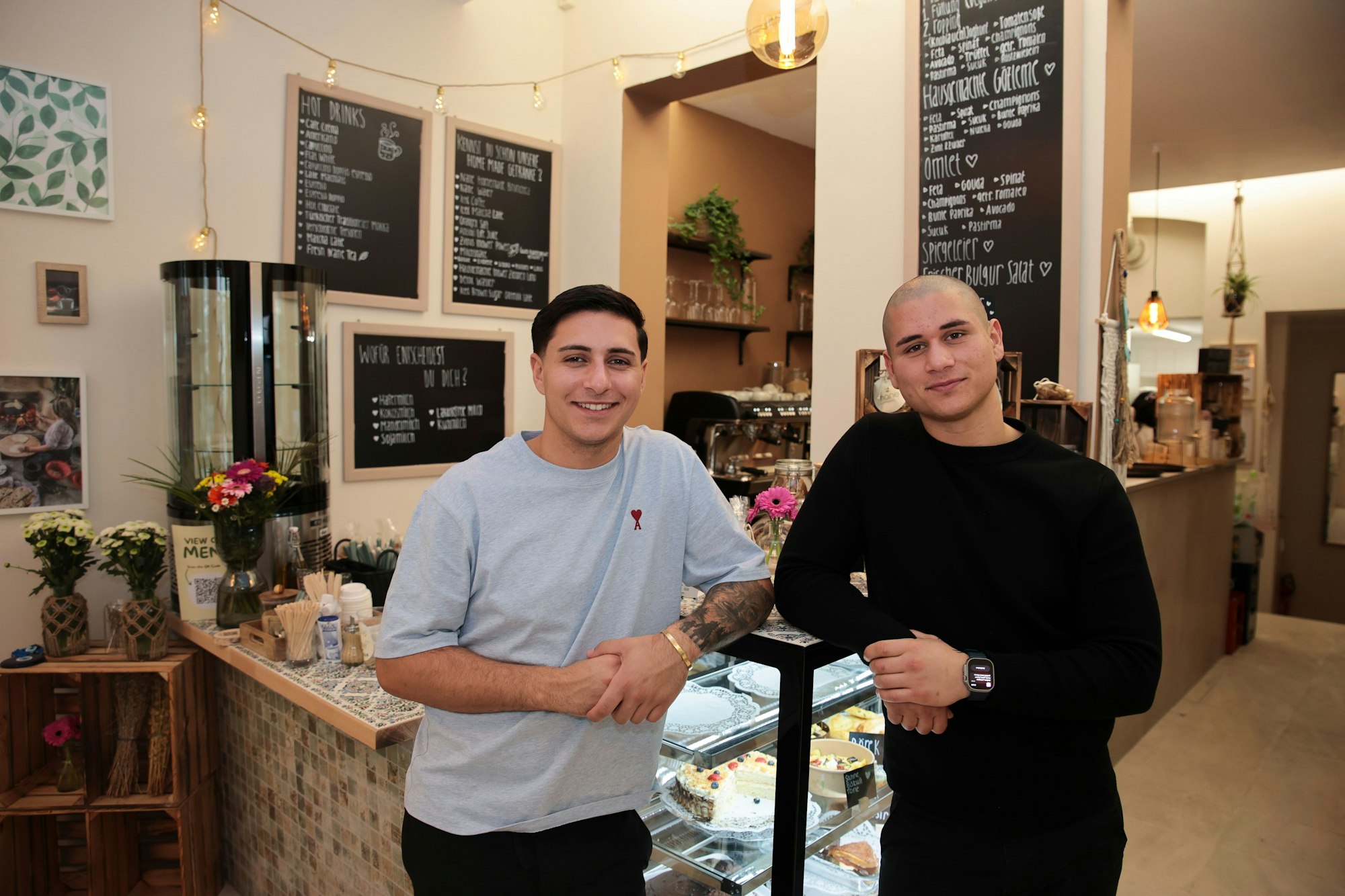 Zwei Männer stehen vor einem Tresen in einem Café.
