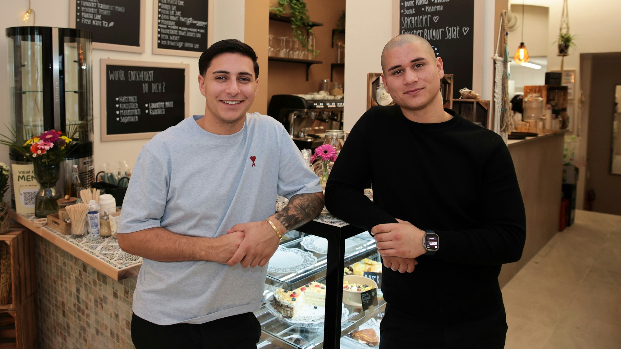 Zwei Männer stehen vor einem Tresen in einem Café.