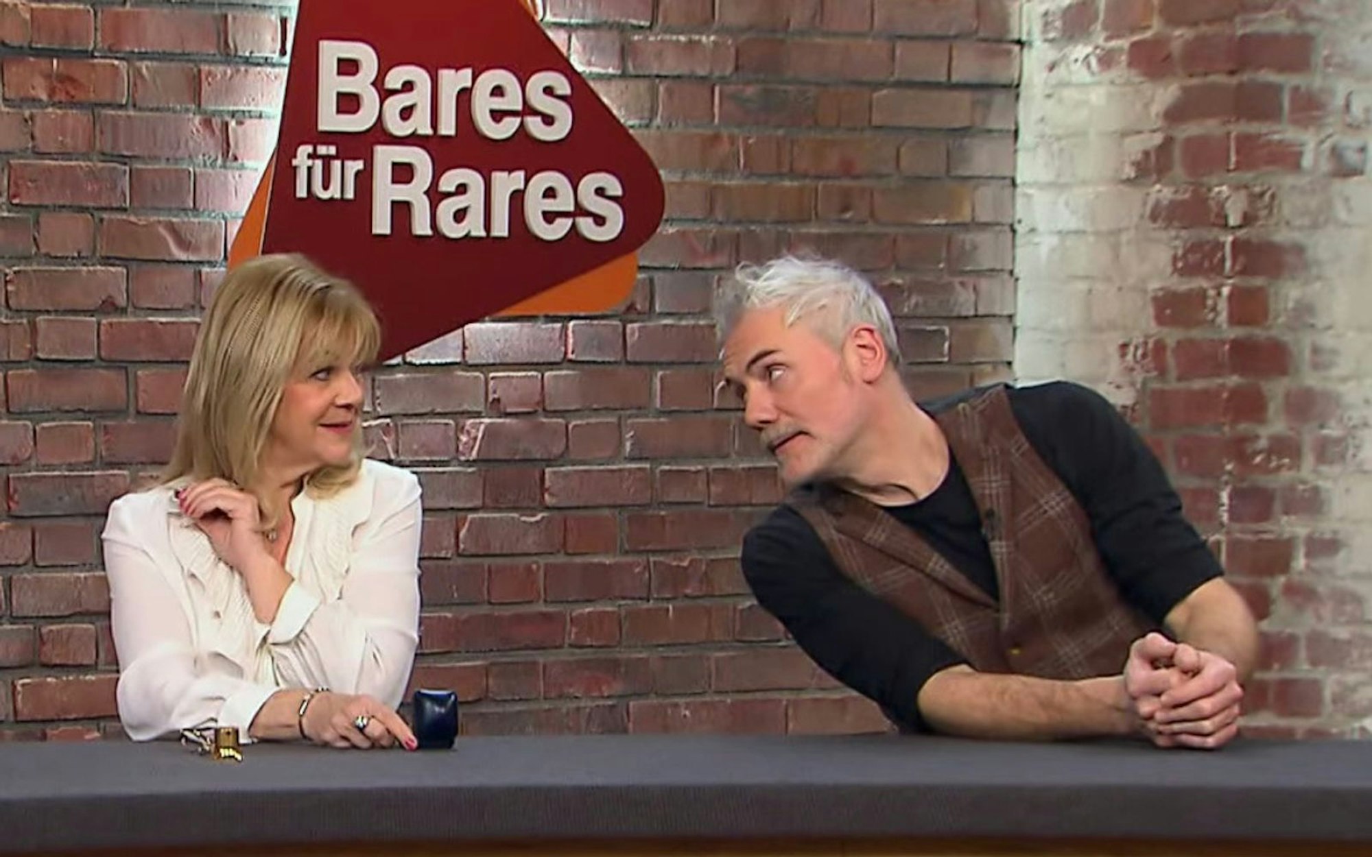 Das Foto stammt aus der ZDF-Trödelshow „Bares für Rares“ und zeigt Händlerin Elke Velten und Händler Christian Vechtel im Gespräch.