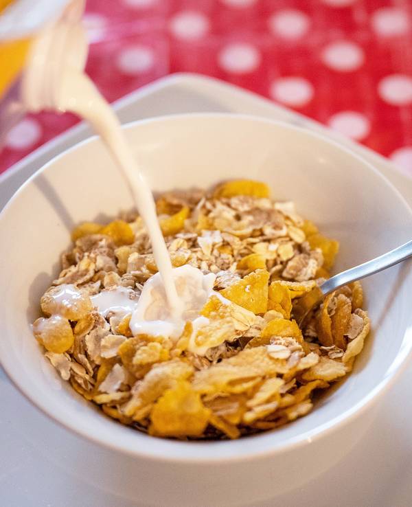 Milch fließt in eine Schale mit Müsli.