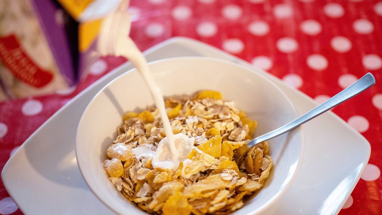 Milch fließt in eine Schale mit Müsli.