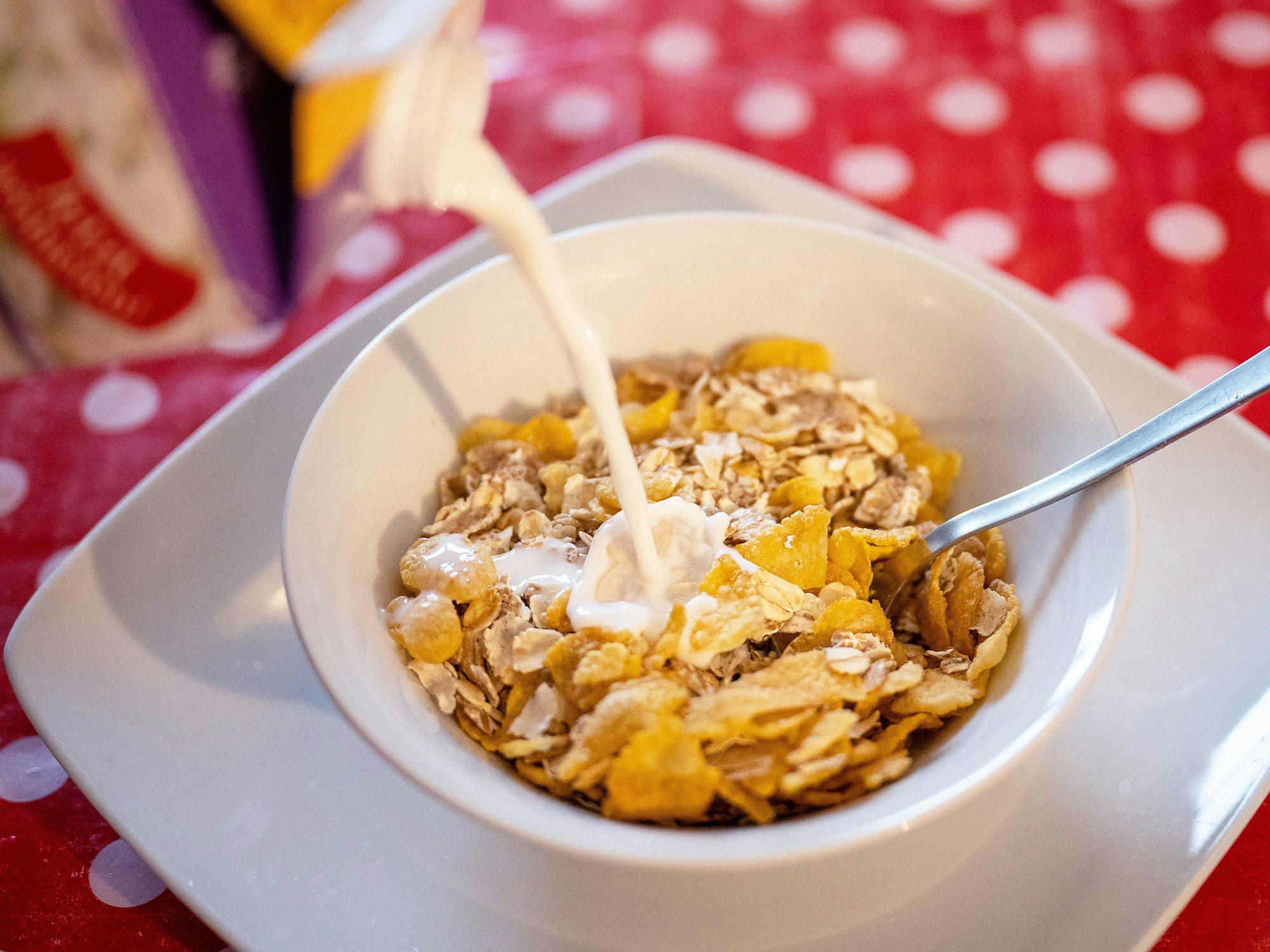 Milch fließt in eine Schale mit Müsli.