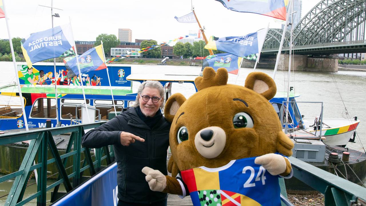 Toni Schumacher legt seinen Arm und Maskottchen Albärt.