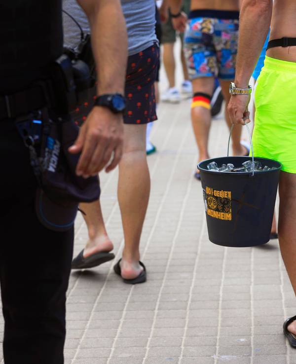 Spanien-Touristen tragen einen Eimer mit dem BVB-Logo mit Flaschen, als sie an der Promenade am Strand Arenal entlang spazieren.