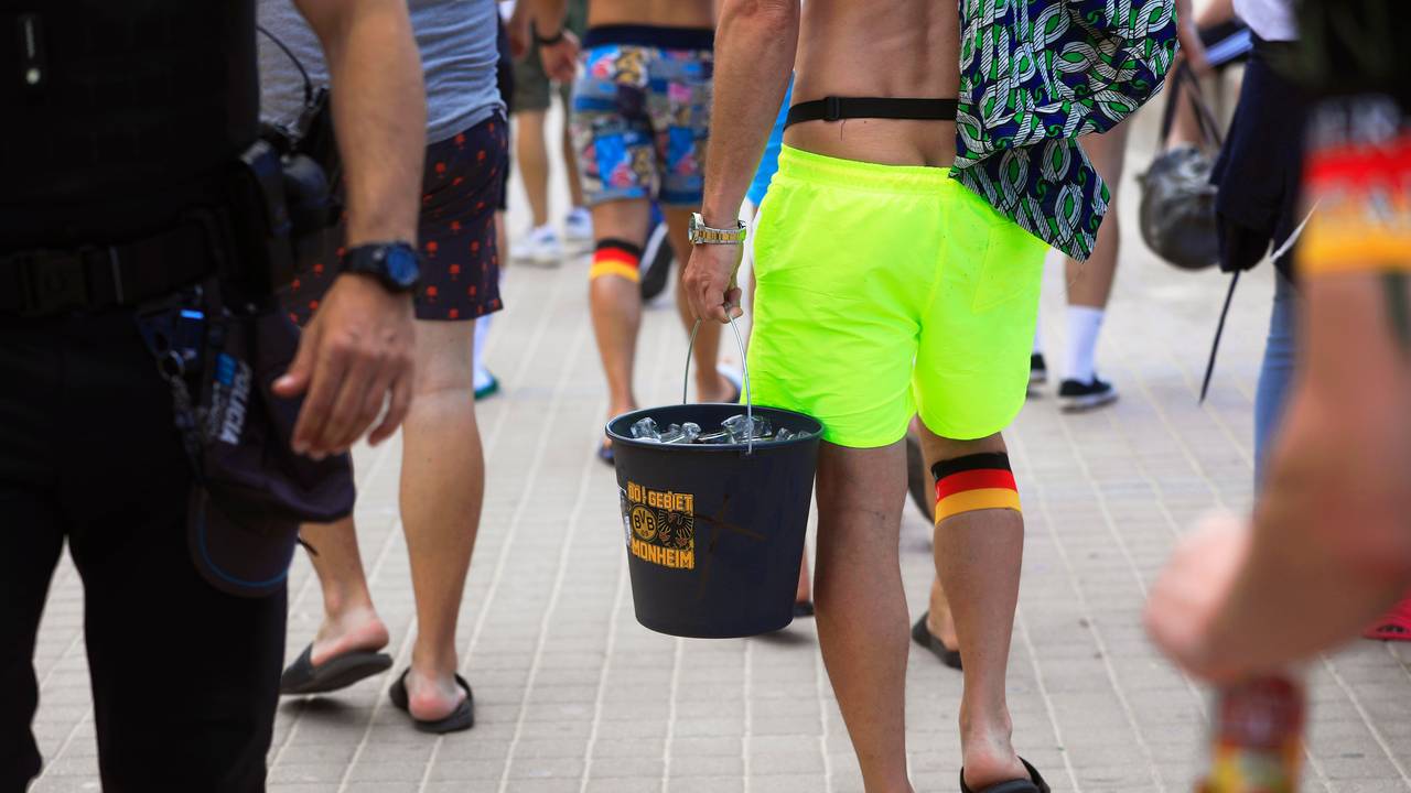 Spanien-Touristen tragen einen Eimer mit dem BVB-Logo mit Flaschen, als sie an der Promenade am Strand Arenal entlang spazieren.