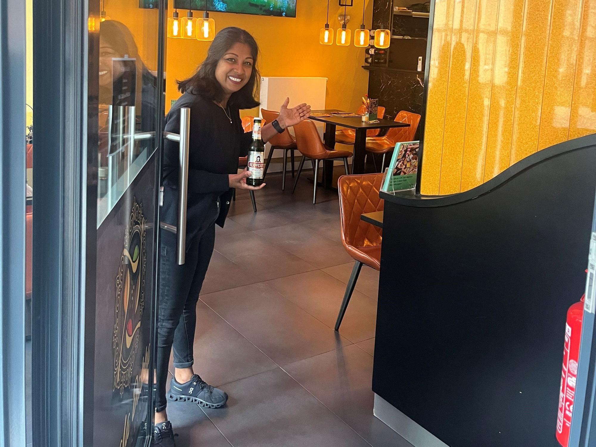 Rushani Gnanes öffnet die Tür zu ihrem Restaurant Masala Dabba und bietet ein Bier an