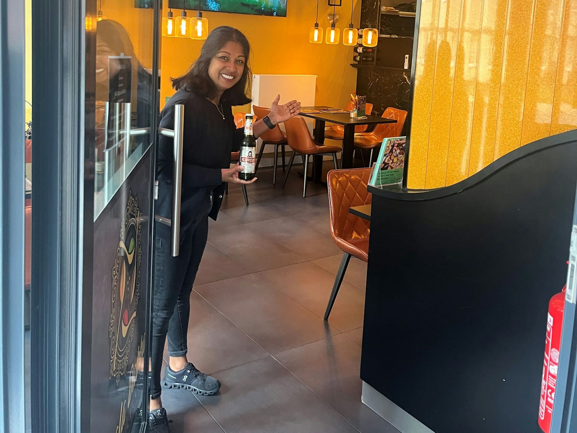 Rushani Gnanes öffnet die Tür zu ihrem Restaurant Masala Dabba und bietet ein Bier an